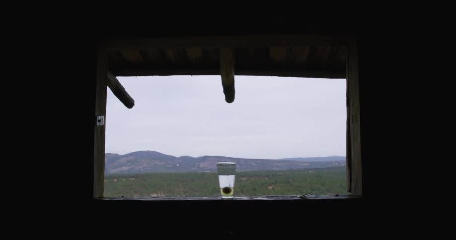 A woman drops an egg into a drink on the windowsill