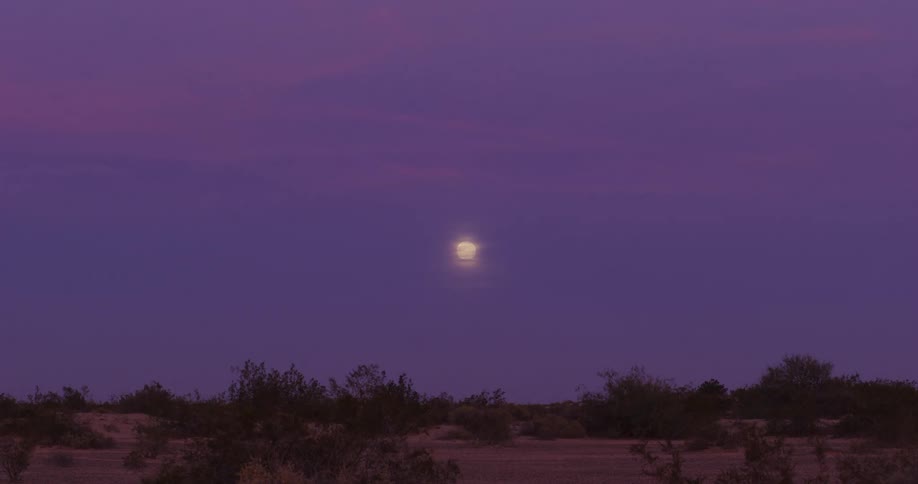 The moon is in the sky above the desert