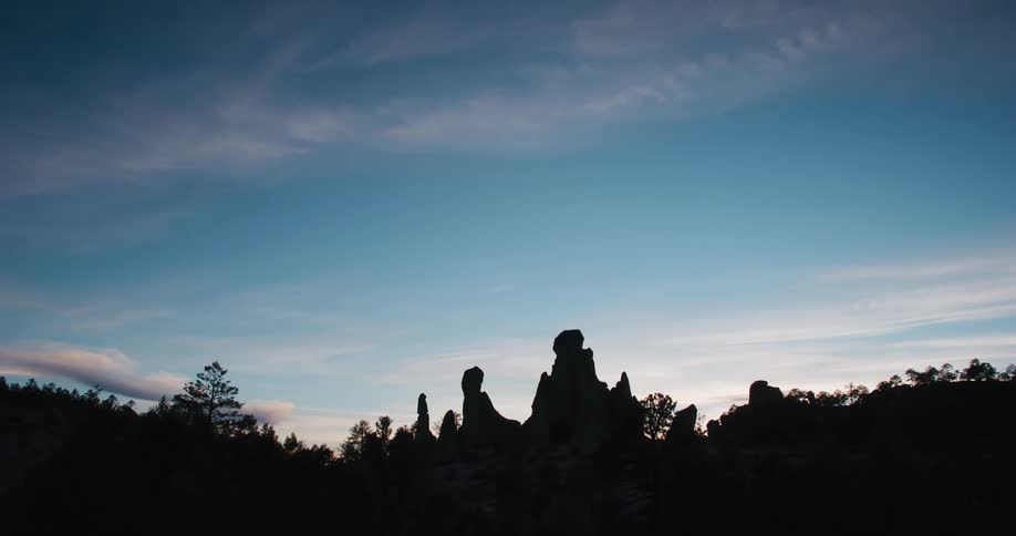Silhouette of rocks and vegetation on a blue sky day with clouds