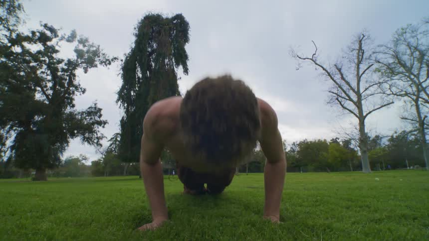 A man is doing pushups on the grass