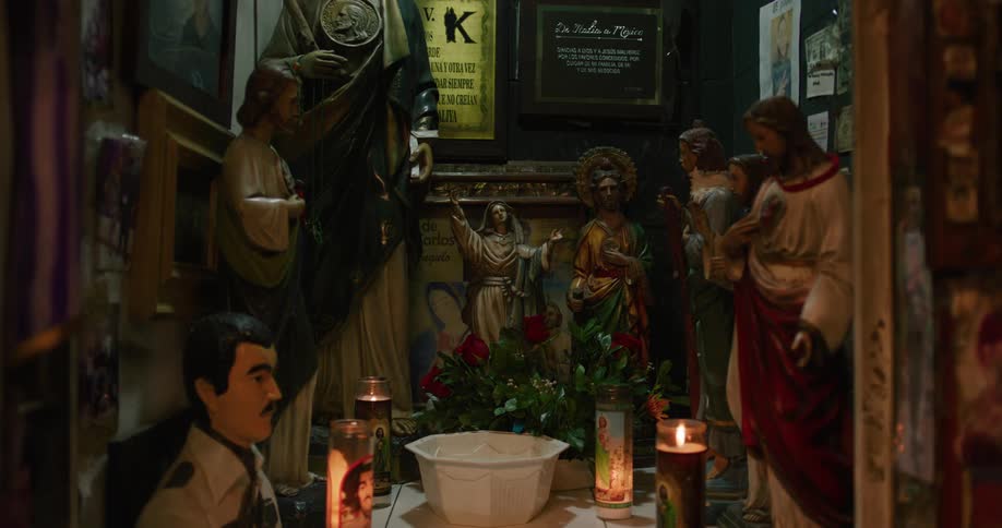 Candles are lit next to statues in a place of worship