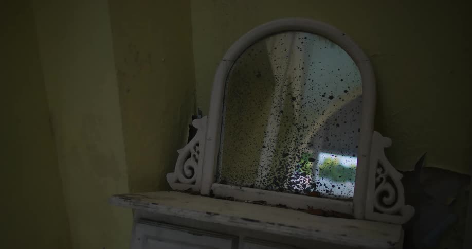 Woman sees her reflection in a dirty mirror