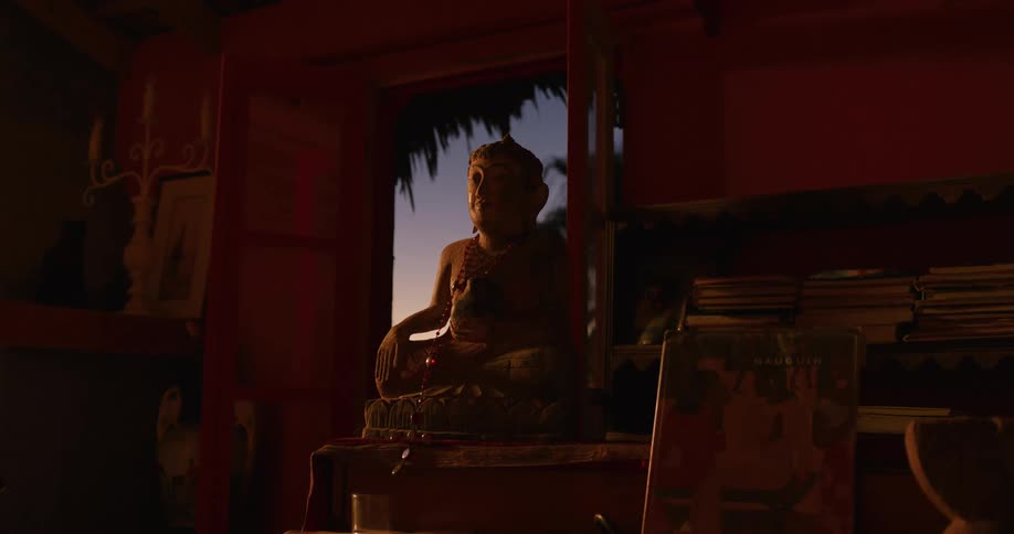 A religious statue is placed inside a house with a door open