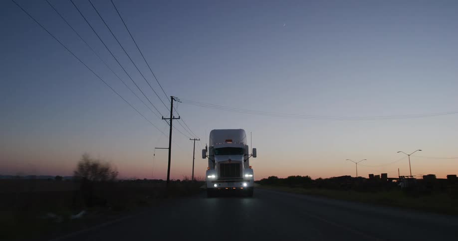 Truck on a road being overtaken by a vehicle on a dark sky day at dawn