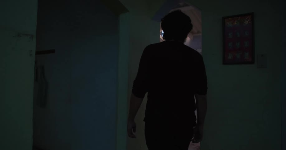 Man walks through a rundown house to look through a window