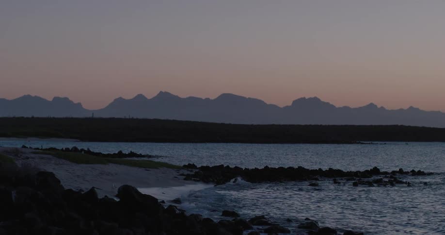 Ocean waves are moving towards the coast while the sun sets