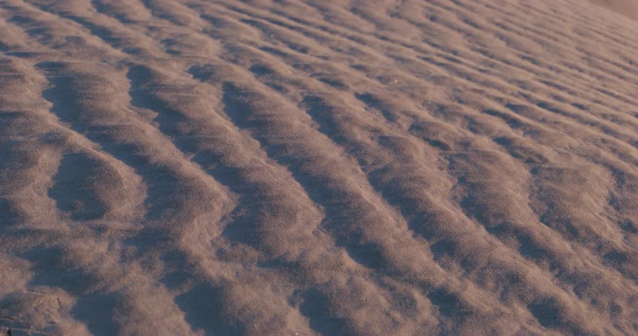 Closeup on a patterned sandy floor with sunlight reflection