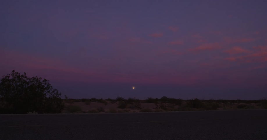 A light shines in the looming darkness in a rural area