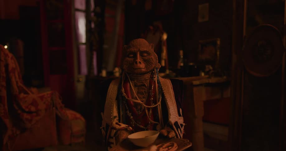 Wooden doll holding a bowl inside a room at night