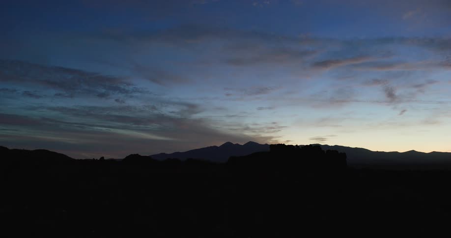 A mountain top while the sun is going down on a cloudy day
