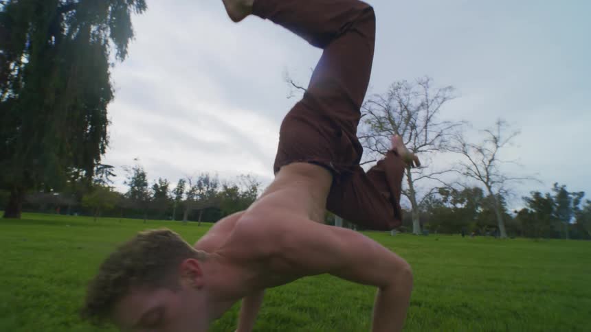 A white male exercises by stretching on a grassy plain