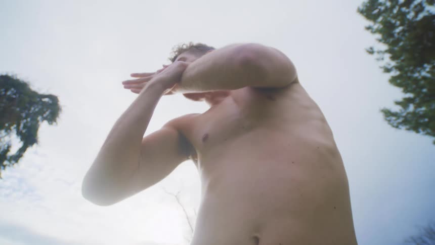 Man is dancing and touching his face outdoors