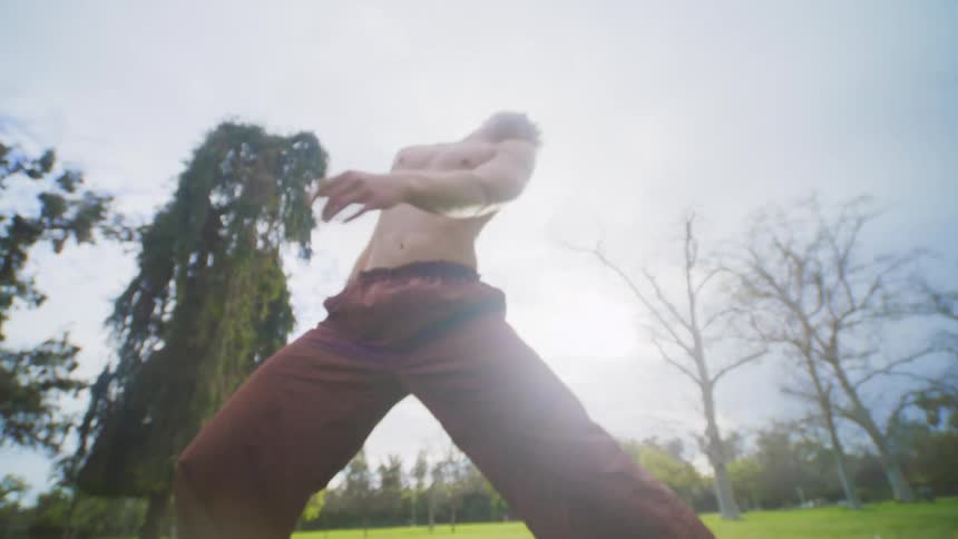 Man is shirtless and dancing outdoors by himself