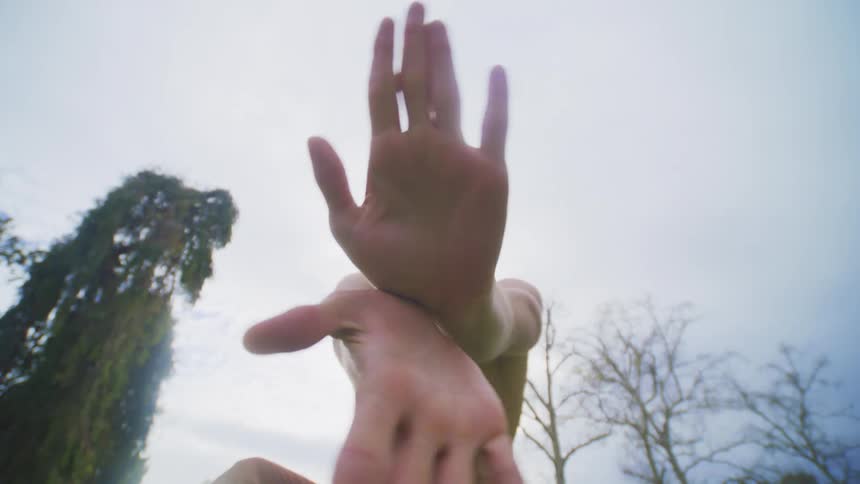 Shirtless man outdoors on a cloudy day dancing and making hand gestures