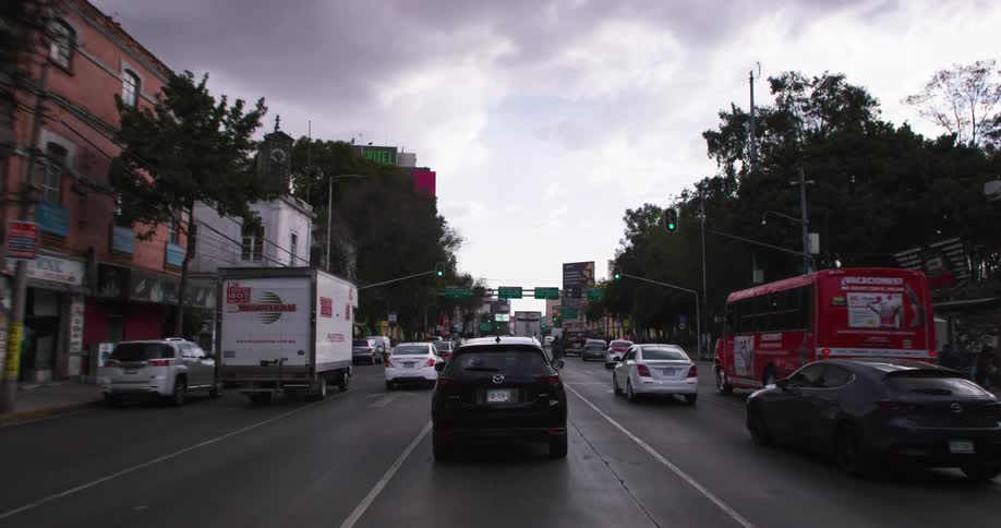 Many vehicles drive down a road in a city