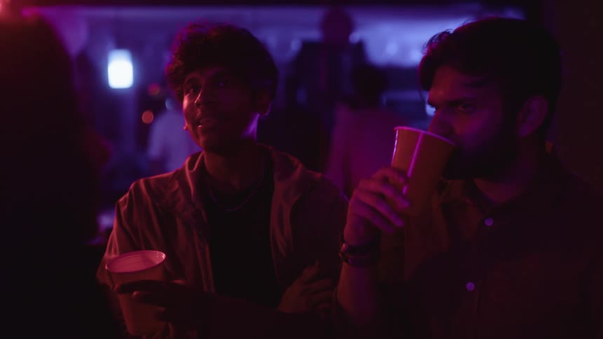 Friends talking and drinking in a lowlit party environment