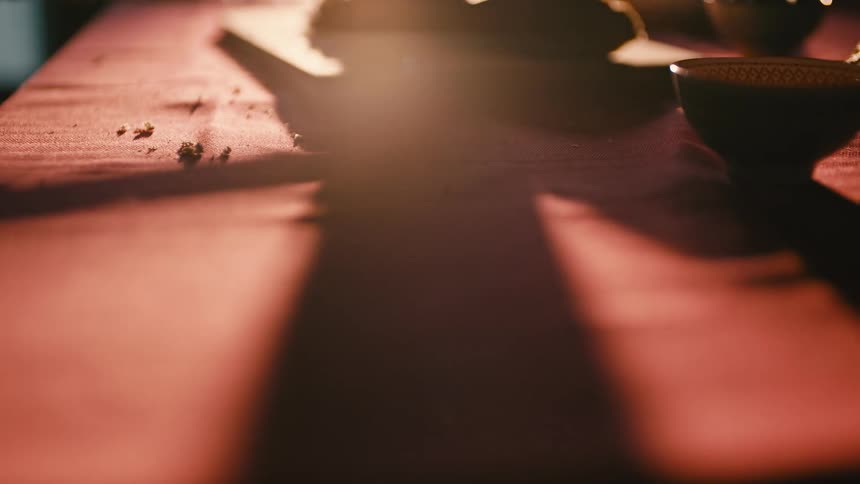 Table with a red tablecloth and a bowl and a shadow moving with a reflection of sunlight