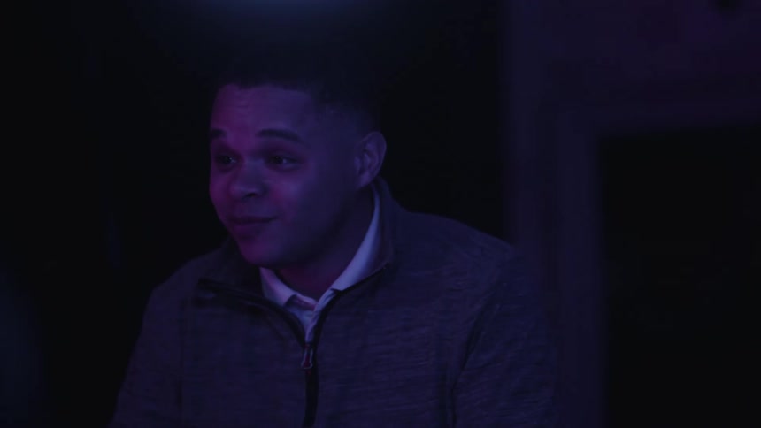 Portrait of a young man sitting in dim light smiling