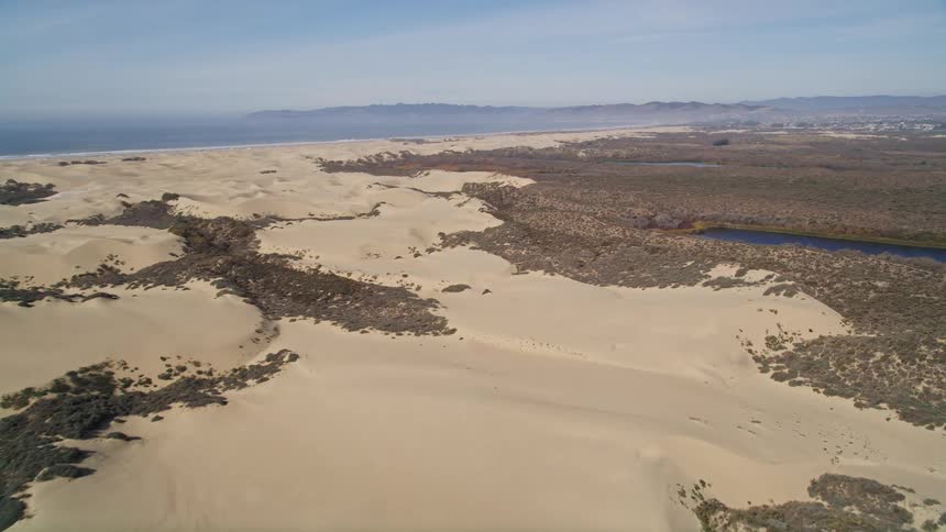A rocky desert gives way to a body of water and a town