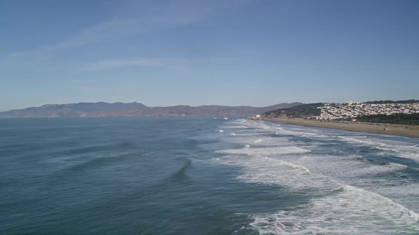 An aerial view of ocean beach moving over the water