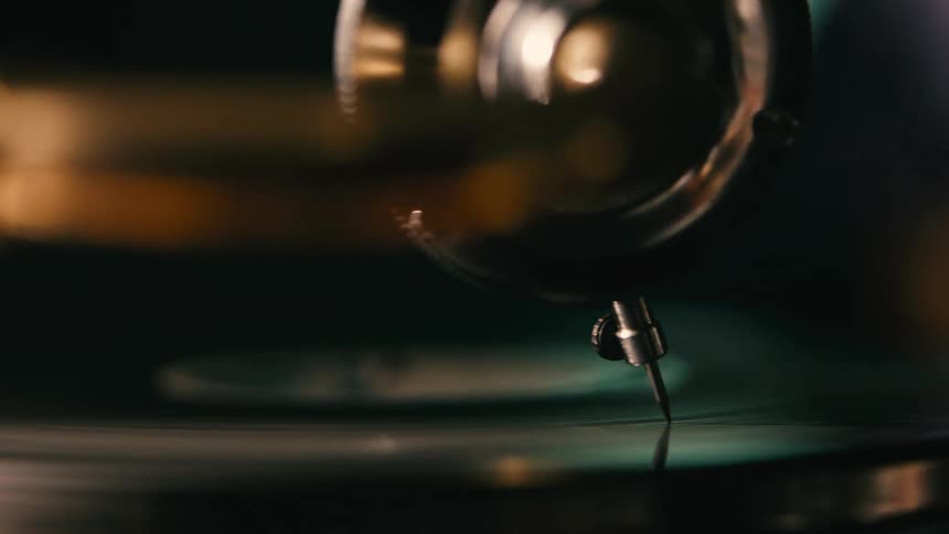 A closeup of a vintage record player playing a black vinyl record