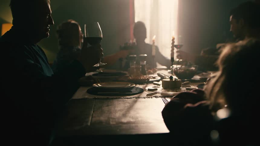 Family and friends gathered around the dining room table toasting before eating their meal