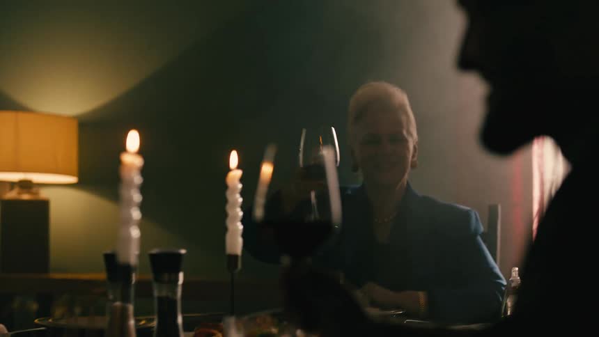 Four people sit at a table drinking wine and talking
