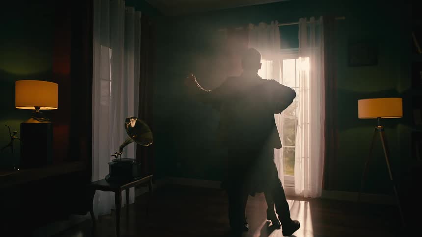 Two people dance together inside a home