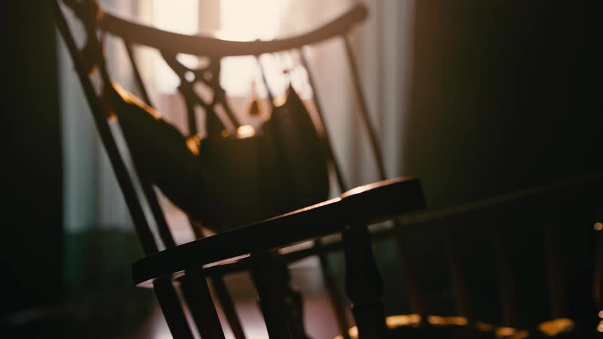 Silhouette of a wooden rocking chair in a dimly lit room