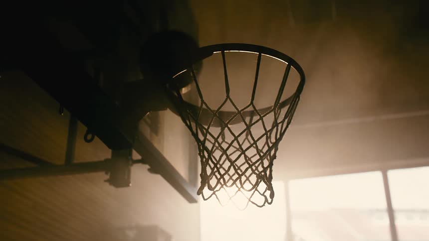 Basketball ball falling into a basket on the court