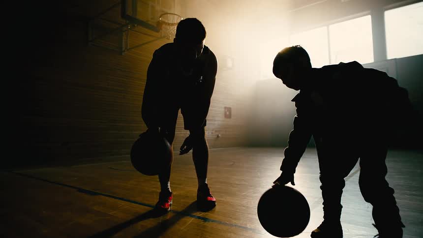 A father teaching his son how to dribble a basketball