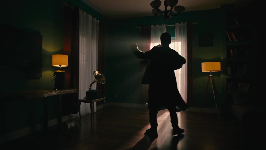 Silhouette of a man and a woman dancing waltz inside a room with a vinyl record playing