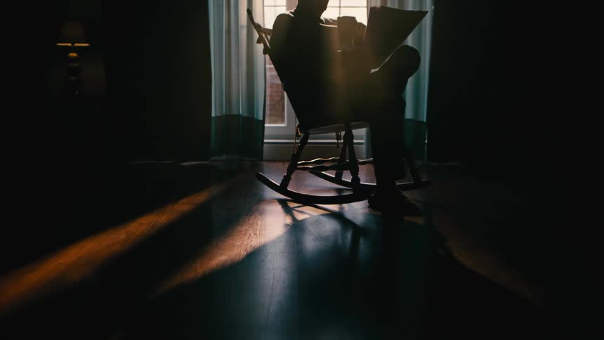 A man reads while sitting in his rocking chair