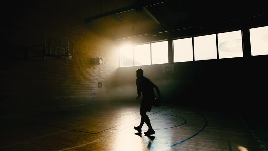 A man picks up a basketball dribbles and makes a shot