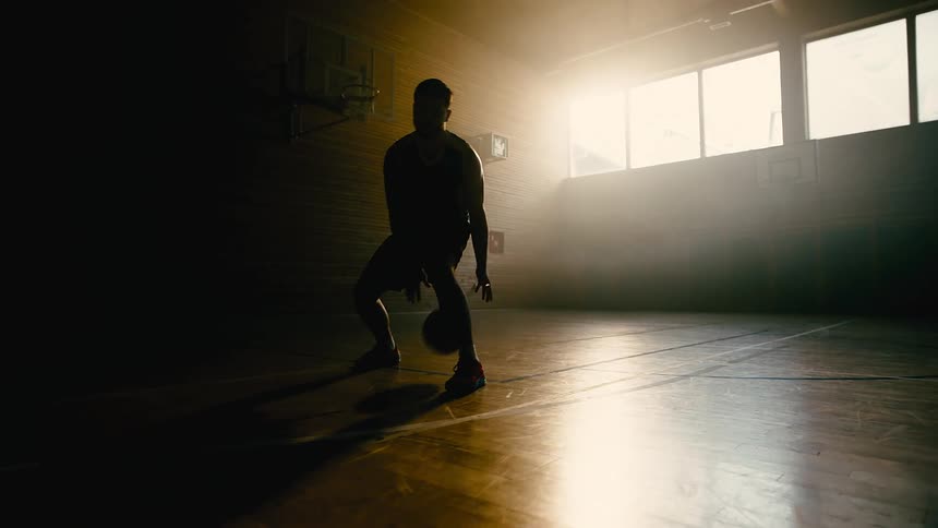 Man on a basketball court training with the ball