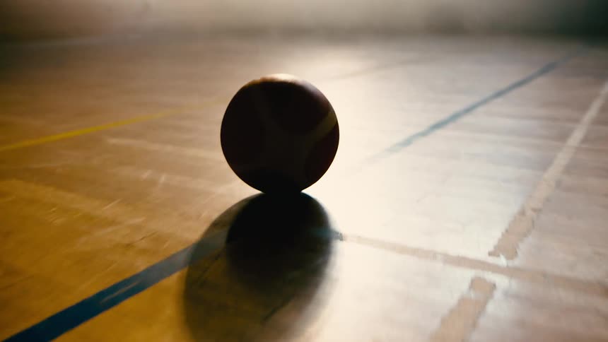 The ball rolls across the wood floor