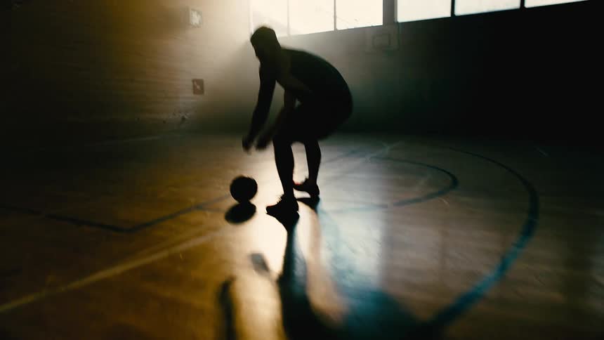 Silhouette of a man catching a ball and shooting it into the basketball hoop