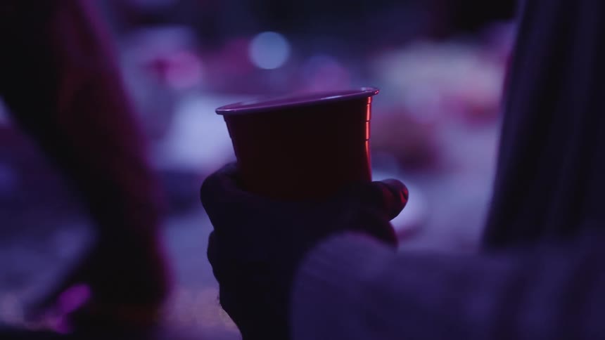 Closeup of a persons hand holding a red disposable cup of drink