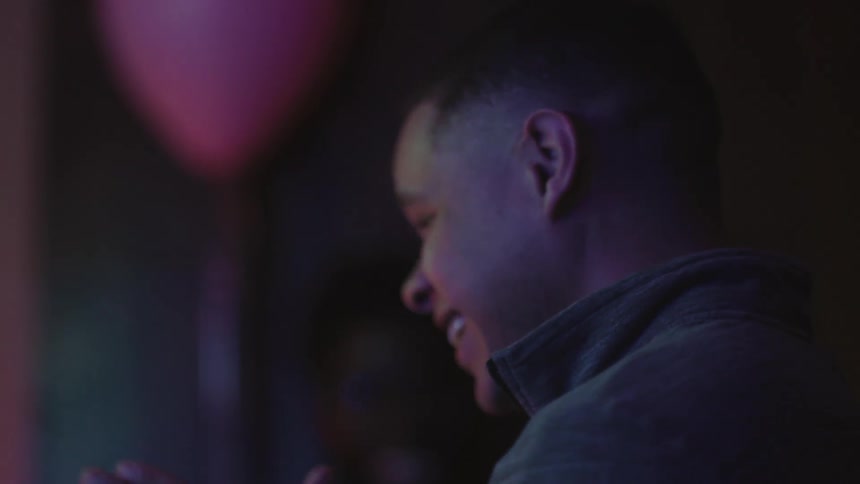A man laughs and claps as he watches something