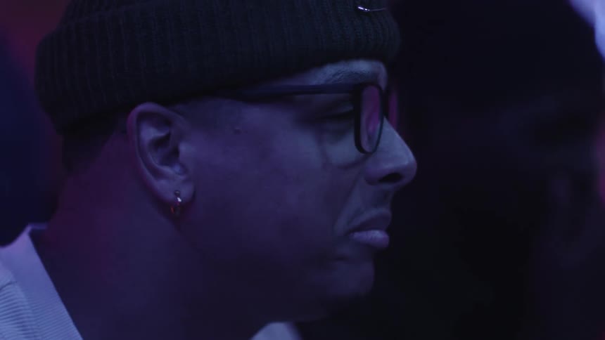 Close up of the face of a man under purple lighting talking at a party