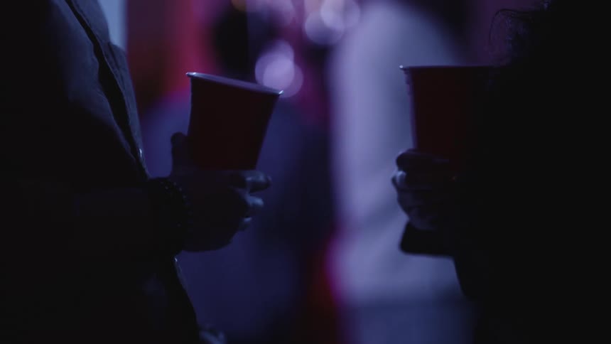 Two people are holding cups at a party