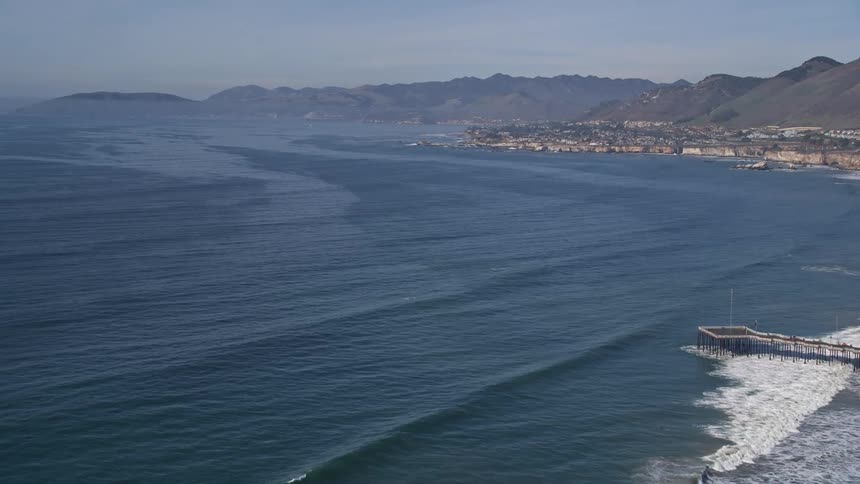 Aerial view of waves crashing on the coast near a small town