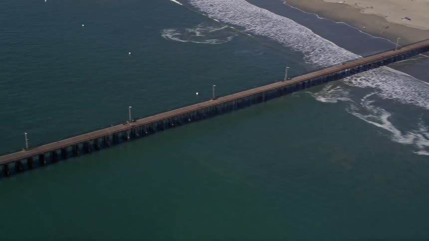 Aerial panorama of a beach with an extensive wooden walkway in the middle of the sea