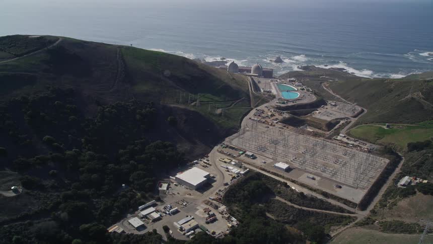 Aerial panorama of power plants and factories by the sea and surrounded by mountains