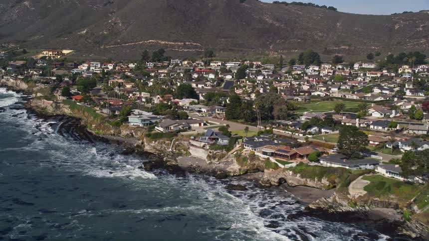 Aerial of waves rolling on shoreline of a coastal residential neighborhood