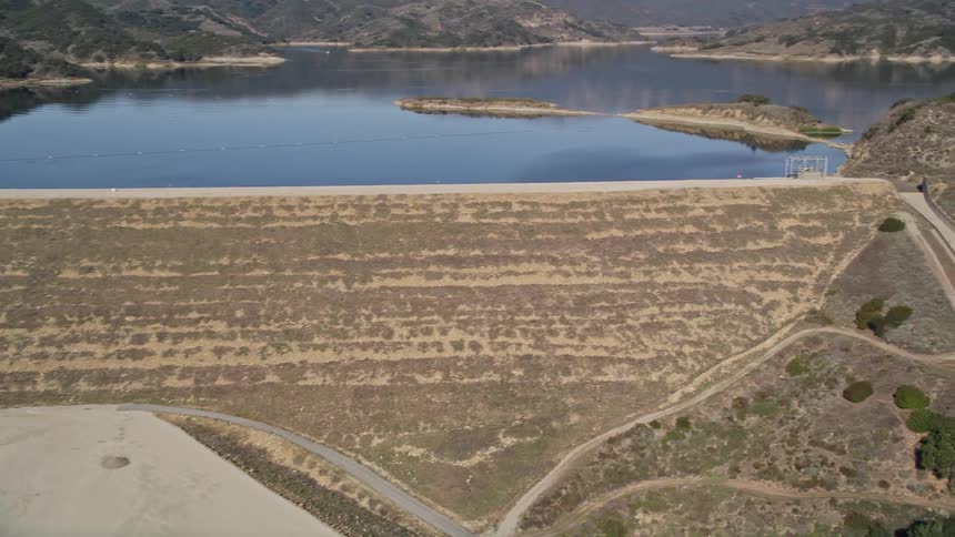 Barren fields near a lake and mountains with scattered trees