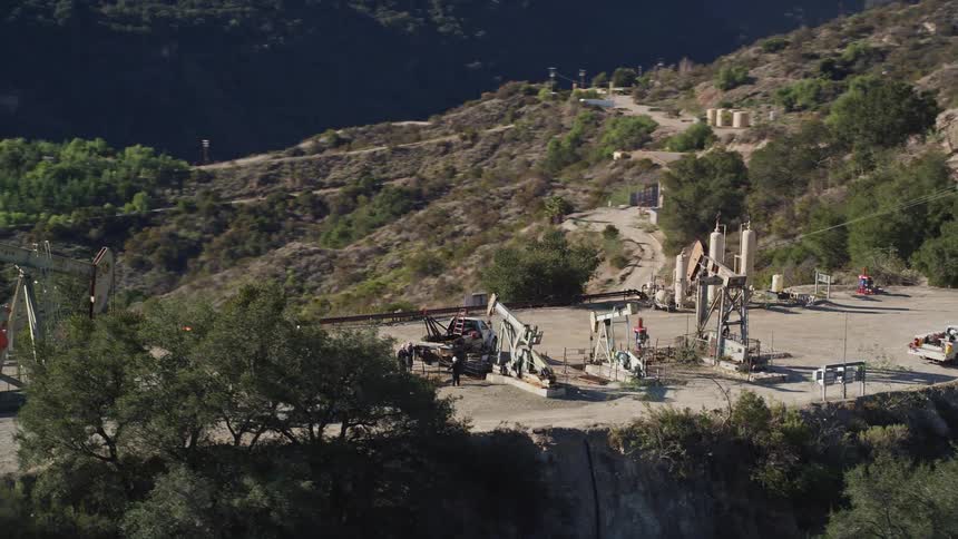 An aerial clip of men digging at a mountain top