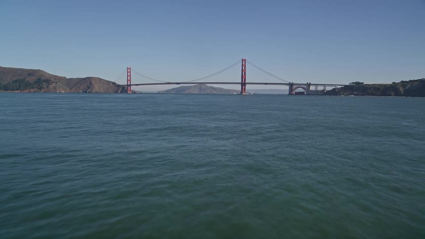 Panorama of a greenish sea and the golden gate bridge in the background