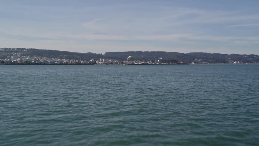 Aerial scenery of a calm sea with an urban city by the mountains on the horizon