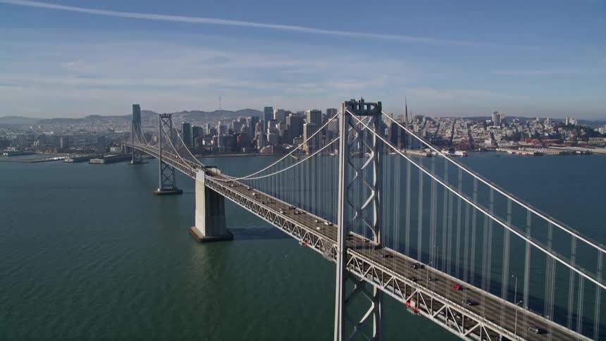 Aerial panorama of an extensive bridge over the sea that provides access to a metropolis with skyscrapers